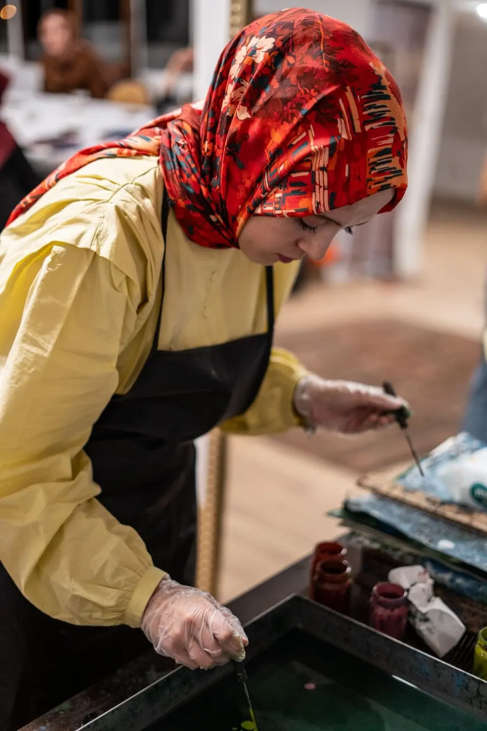 Ebru teknesine fırçayla boya serpen katılımcı