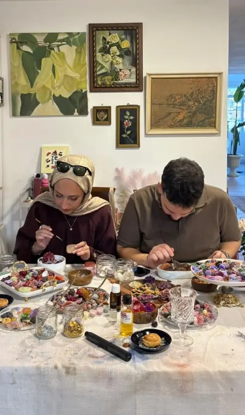 Tablolarla dolu atölyede masada üreten katılımcılar