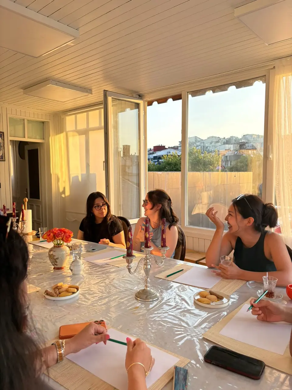 Zezu’da güneşli bir masanın etrafında sohbet eden Speaking Club katılımcıları