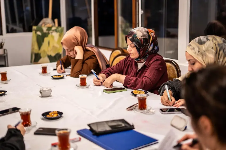 Speaking Club buluşmasında masa etrafında not alan katılımcılar