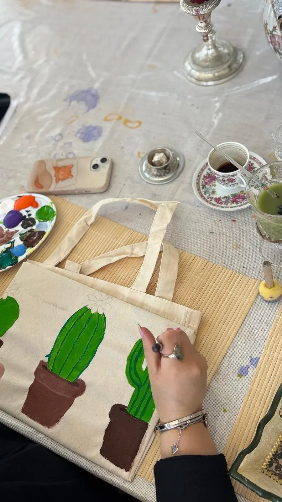 Bez çantaya kaktüs deseni boyayan katılımcının elleri